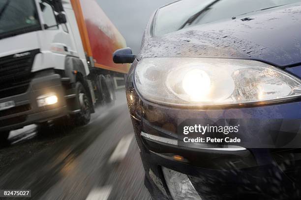 car and lorry on motorway in the rain - dépasser photos et images de collection