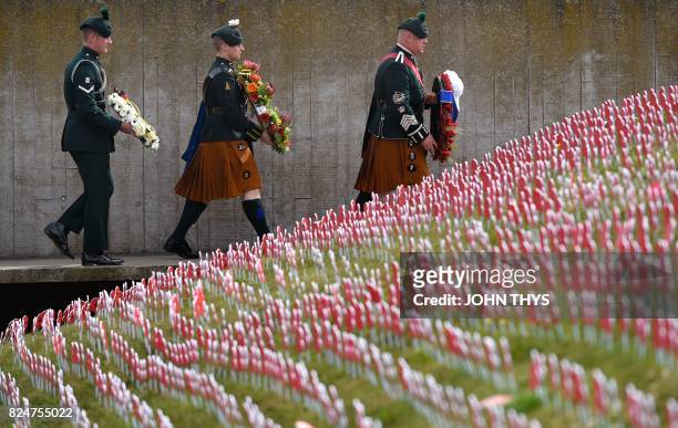 Members of the Royal Irish Fusiliers carry wreaths as they walks past cut out poppies with messages written on them dedicated to the soldiers who...