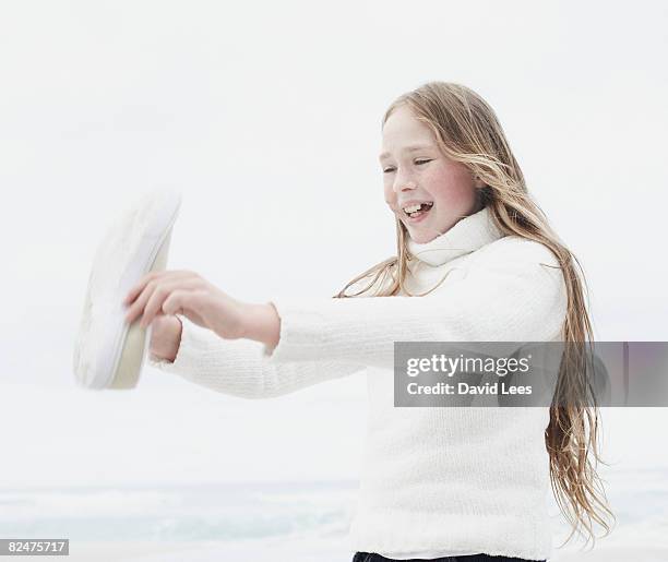 girl (10-12) emptying sand from shoe on beach - girl 11 12 laughing close up foto e immagini stock