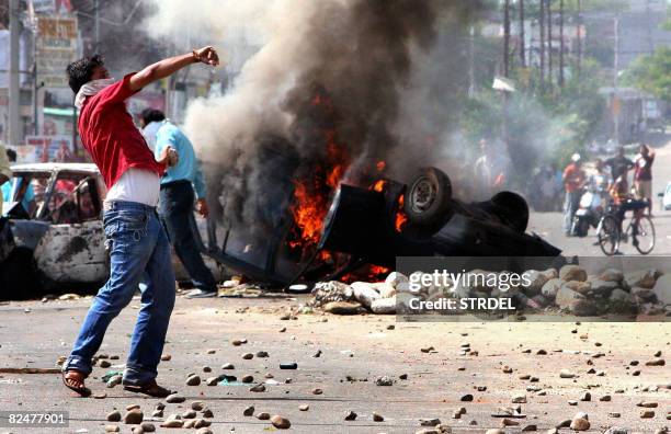 An Indian Hindu demonstrator throws stones toward the police during a protest against the revoking of an order awarding land to a Hindu pilgrimage...