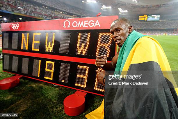 Usain Bolt of Jamaica poses next to the clock after breaking the world record with a time of 19.30 to win the gold medal in the Men's 200m Final at...