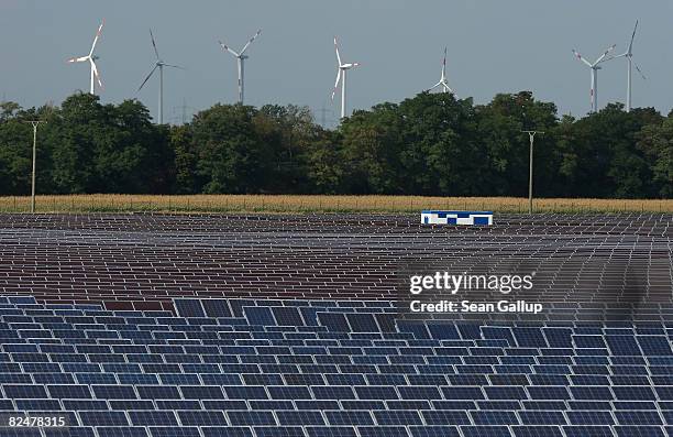 Wind turbines spin behind a field of solar cell panels near the headquarters and production facilities of German solar cells producer Q-Cells on...