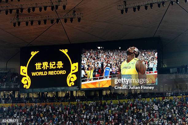 Usain Bolt of Jamaica is seen on the jumbotron as he reacts after breaking the world record with a time of 19.30 to win the gold medal in the men's...