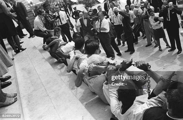 Black and white people chain themselves and sit in front of the New York City Hall, on August 23 during a protest against segregation in some of...