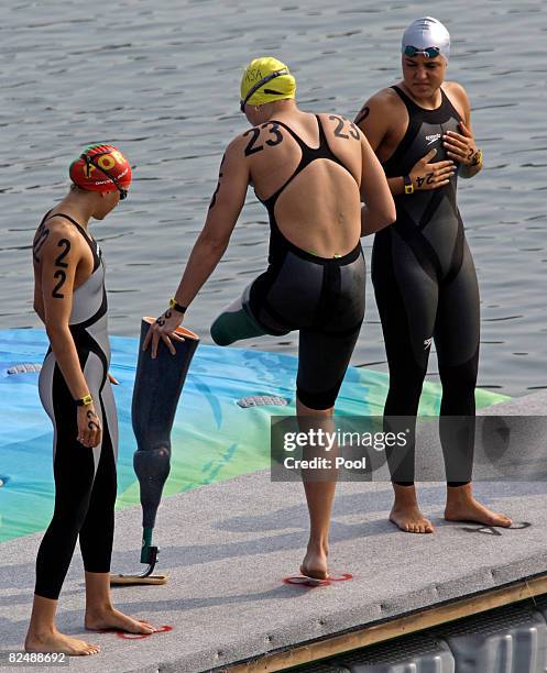 Daniela Inacio of Portugal and Martina Grimaldi of Italy look on as Natalie Du Toit of South Africa removes her prosthetic leg as she prepares to...