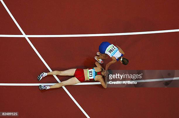 Tatiana Sibileva of Russia helps up Ryta Turava of Belarus from the track after the Women's 20km Walk Final held at the National Stadium during Day...