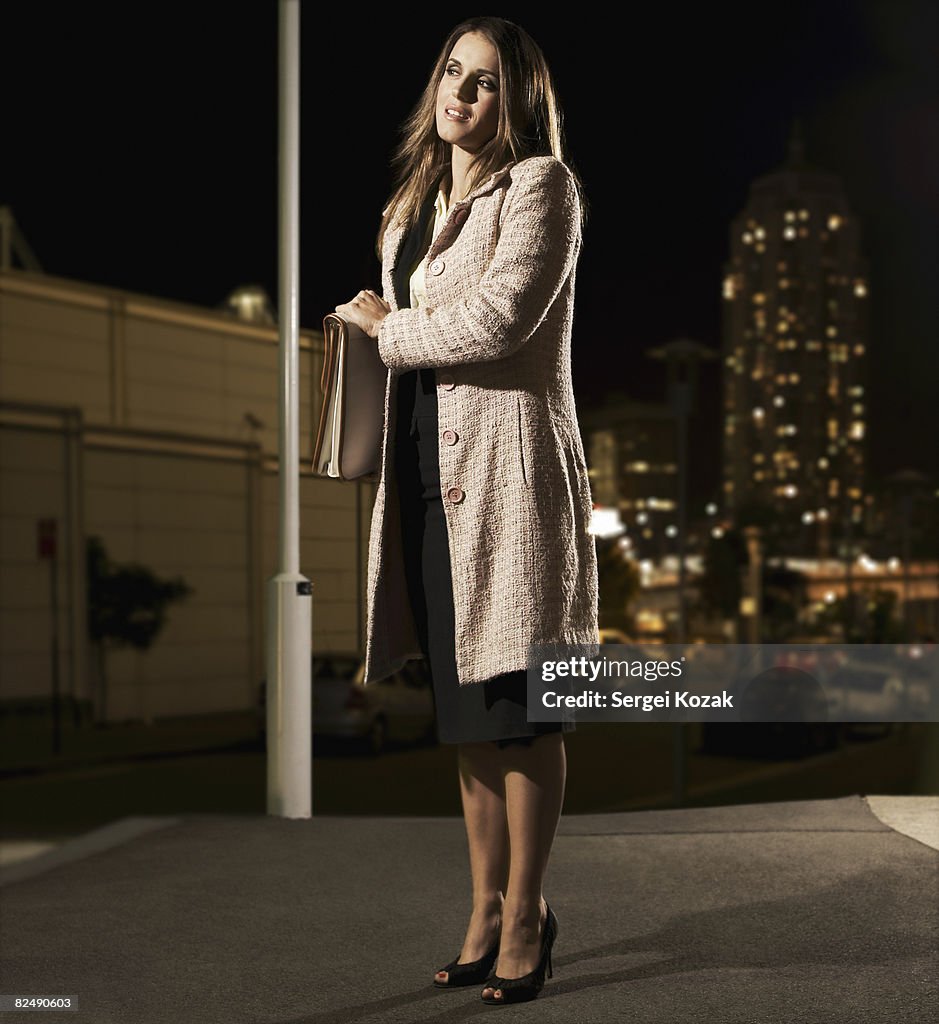 Woman standing on urban street with briefcase 