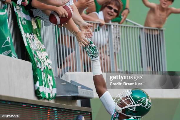 Duron Carter of the Saskatchewan Roughriders gives the football to a young fan after scoring a touchdown in the game between the Toronto Argonauts...