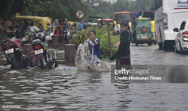 Children enjoy rain water as vehicles wade through logged rain water during a heavy rainfall at Delhi Gate on July 31, 2017 in New Delhi, India....