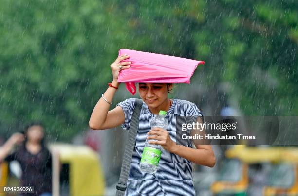 People caught in the monsoon rain at Connaught Place on July 31, 2017 in New Delhi, India. Delhiites woke up to a drenched morning as rains hit the...