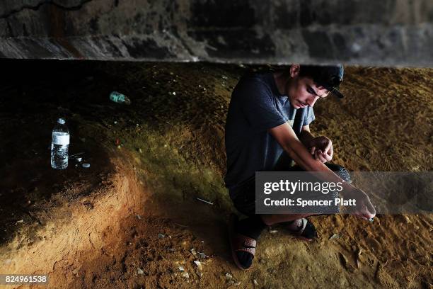 Mike a heroin addict who began using opiates when he was 13, pauses to shoot-up by a railway underpass in the Kensington section of Philadelphia...