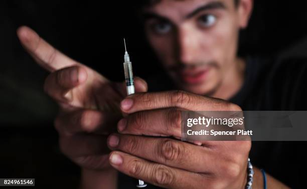 Mike a heroin addict who began using opiates when he was 13, pauses to shoot-up by a railway underpass in the Kensington section of Philadelphia...