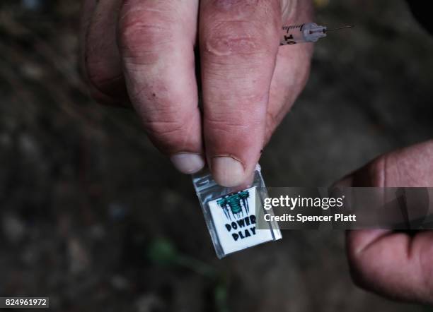 Chris, a homeless heroin addict, displays a brand of heroin called "power play" which was purchased on the street for $5 near a railway underpass in...