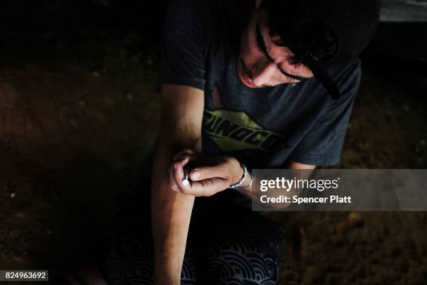 Mike a heroin addict who began using opiates when he was 13, pauses to shoot-up by a railway underpass in the Kensington section of Philadelphia...