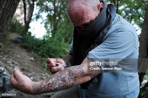 Chris, a homeless heroin addict, pauses to shoot-up by a railway underpass in the Kensington section of Philadelphia which has become a hub for...