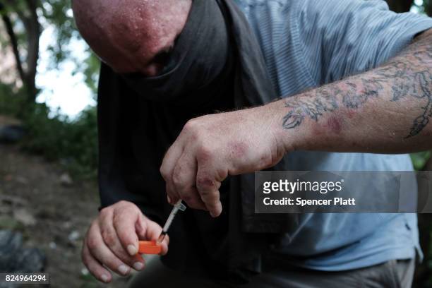 Chris, a homeless heroin addict, pauses to shoot-up by a railway underpass in the Kensington section of Philadelphia which has become a hub for...