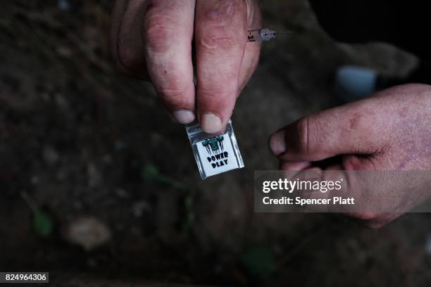 Chris, a homeless heroin addict, displays a brand of heroin called "power play" which was purchased on the street for $5 near a railway underpass in...
