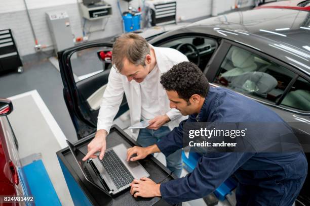 mechanics working together at an auto repair shop using a computer - medical transportation stock pictures, royalty-free photos & images