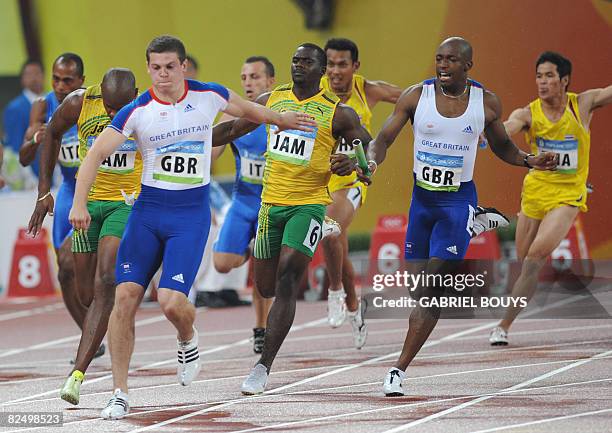 Britain's Marlon Devonish hands the baton to Craig Pickering during the men's 4x100m relay qualification heat at the National Stadium in the 2008...