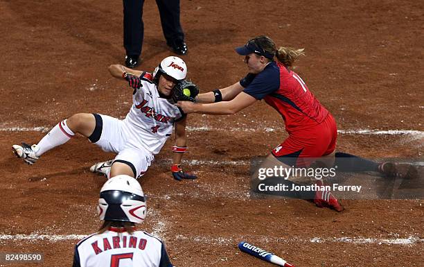 Megu Hirose of Japan slides into home safely as catcher Stacey Nuveman of the United States drops the ball during the women's grand final gold medal...