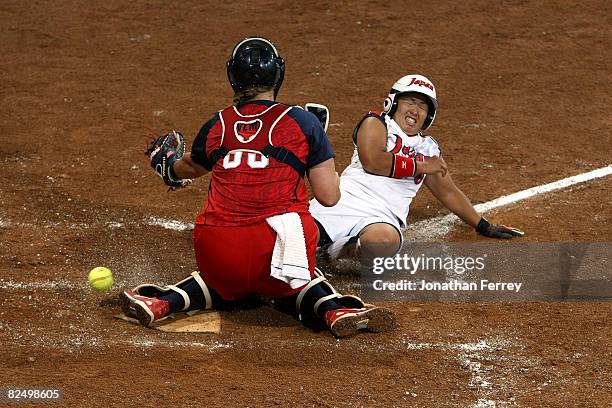 Megu Hirose of Japan slides into home safely as catcher Stacey Nuveman of the United States drops the ball during the women's grand final gold medal...
