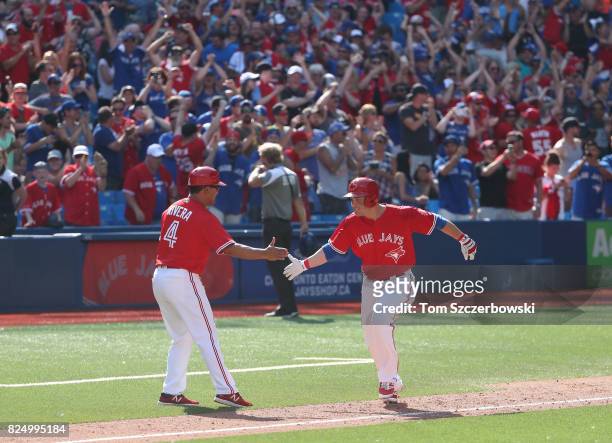 Steve Pearce of the Toronto Blue Jays is congratulated by third base coach Luis Rivera after hitting a game-winning grand slam home run in the ninth...