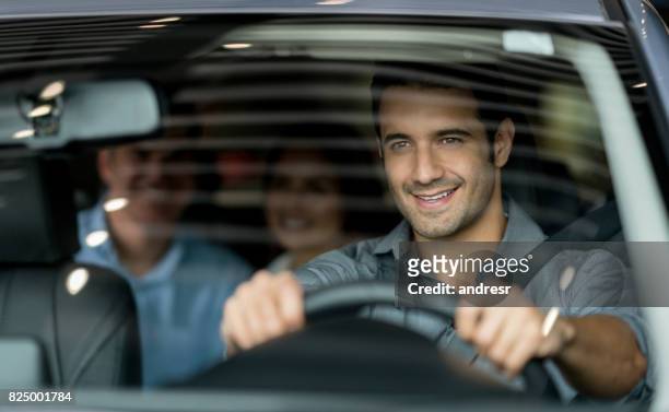 crowdsource taxi driver driving a couple of customers - mid adult men stock pictures, royalty-free photos & images