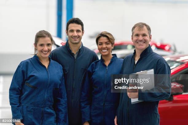 glückliche gruppe der mechanik arbeiten bei einer autowerkstatt - automechaniker stock-fotos und bilder