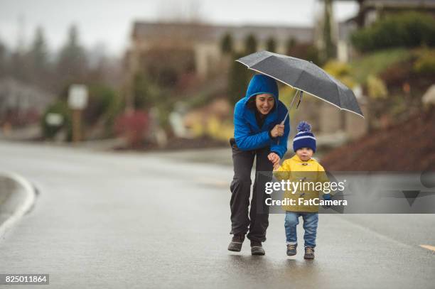 family walk in the rain - yellow umbrella stock pictures, royalty-free photos & images