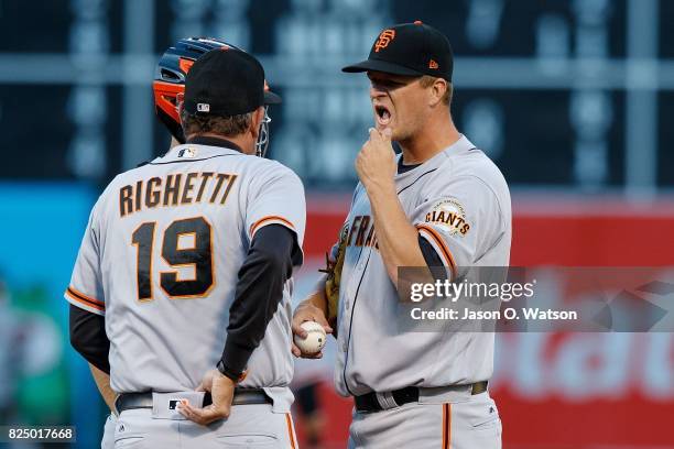 Dave Righetti of the San Francisco Giants talks to Matt Cain on the pitchers mound against the Oakland Athletics during the first inning at the...