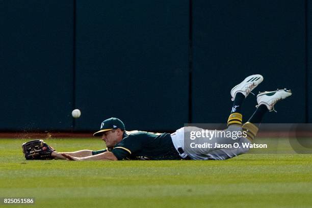 Jaycob Brugman of the Oakland Athletics dives for but is unable to catch a fly ball hit for a double by Brandon Crawford of the San Francisco Giants...