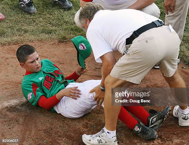 Trainer looks at the knee of pitcher Carlos Balboa of Mexico after Balboa was hit by a line drive in the sixth inning against Latin America during...