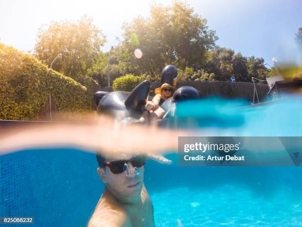 happy couple taking a selfie enjoying summer in swimming pool with big inflatable black swan sunbathing and relaxing in the sun during weekend. - hot big women stockfoto's en -beelden