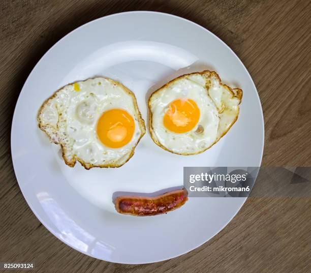 smiling face on white plate made with fried egg & sausage. - scrambled eggs stock pictures, royalty-free photos & images
