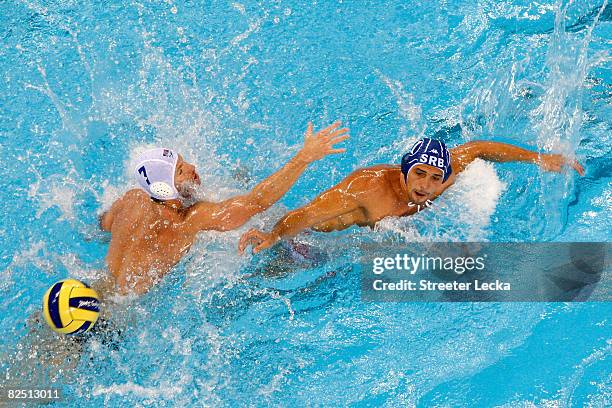 Vladimir Vujasinovic of Serbia passes the ball around Layne Beaubien of the United States in the men's semifinal water polo match at the Yingdong...