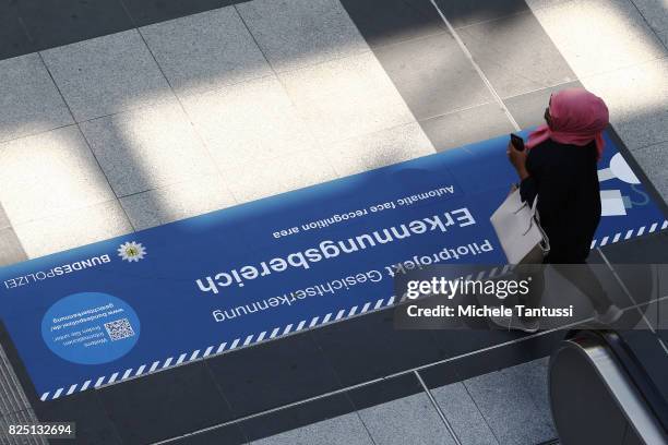 Passengers walk by a security sign warning for a Face recognition area at the Suedkreuz train station on August 1, 2017 in Berlin, Germany. German...