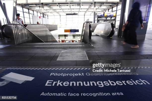 Passengers walk by a security sign warning for a Face recognition area at the Suedkreuz train station on August 1, 2017 in Berlin, Germany. German...