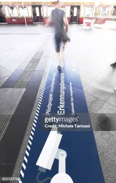 Passengers walk by a security sign warning for a Face recognition area at the Suedkreuz train station on August 1, 2017 in Berlin, Germany. German...