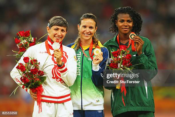 Silver medalist Tatyana Lebedeva of Russia, gold medalist Maurren Higa Maggi of Brazil and bronze medalist Blessing Okagbare of Nigeria hold up their...