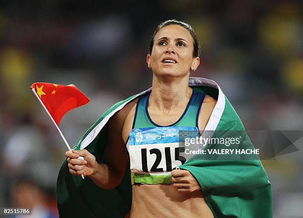 Brazil's Maurren Higa Maggi waves a Chinese flag as she celebrates winning the women's long jump final at the "Bird's Nest" National Stadium during...