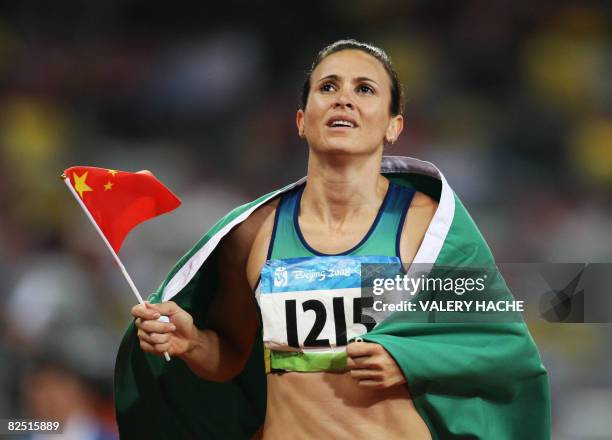 Brazil's Maurren Higa Maggi waves a Chinese flag as she celebrates winning the women's long jump final at the "Bird's Nest" National Stadium during...