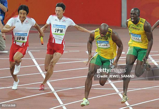 Jamaica's Asafa Powell runs with the baton handed over to him by teammate Usain Bolt as they compete against Japan's Shinji Takahira and teammate...