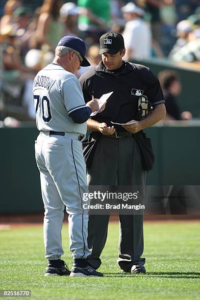 General manager Joe Maddon of the Tampa Bay Rays discusses fielding changes with home-plate umpire James Hoye during the game against the Oakland...