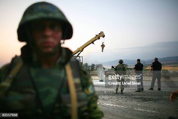 Russian peace keeping troops remove a concrete barrier as they pull out from the last checkpoint they control, near Kharvaleti, on the road from...