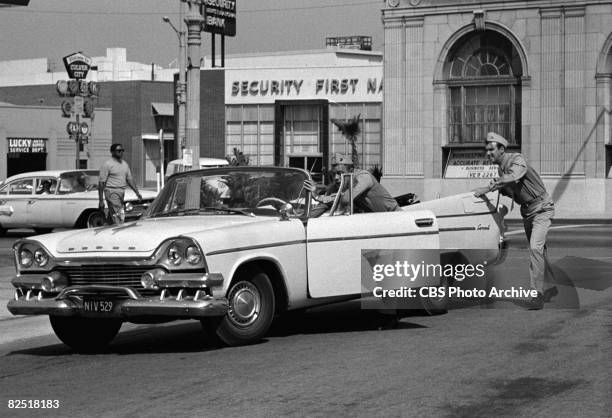 American actor Frank Sutton and Jim Nabors push a convertible along a street in a scene from an episode of the television comedy series 'Gomer Pyle,...