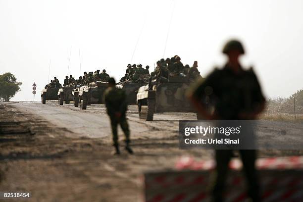 Russian soldiers ride in a convoy of armoured personnel carriers as they pull out from the last checkpoint they control, near Kharvaleti, on the road...