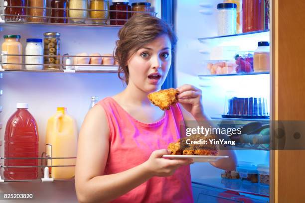 jeune femme malsaine manger devant le réfrigérateur - woman eating chicken photos et images de collection