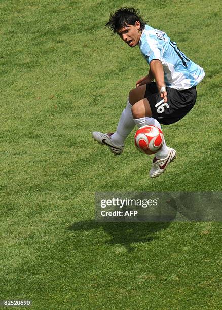 Argentinian forward Sergio Aguero jumps with the ball over Nigerian goalkeeper Ambruse Vanzekin during the men's Olympic football final Argentina vs....