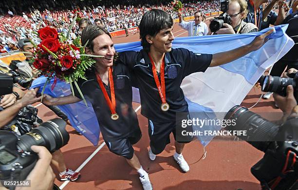 Argentinian forwards Lionel Messi and Sergio Aguero, wrapped in their national flag, pose during the men's Olympic football tournament medal ceremony...