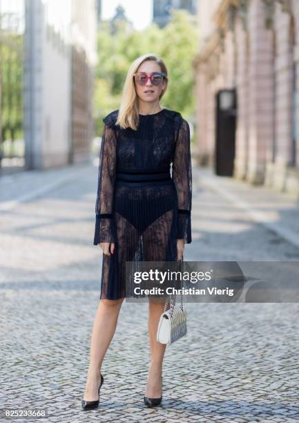 Sonia Lyson wearing a navy sheer cocktail party dress with long sleeves from Tara Jarmon, a silver Miu Miu bag, MCM sunglasses, black Gianvito Rossi...